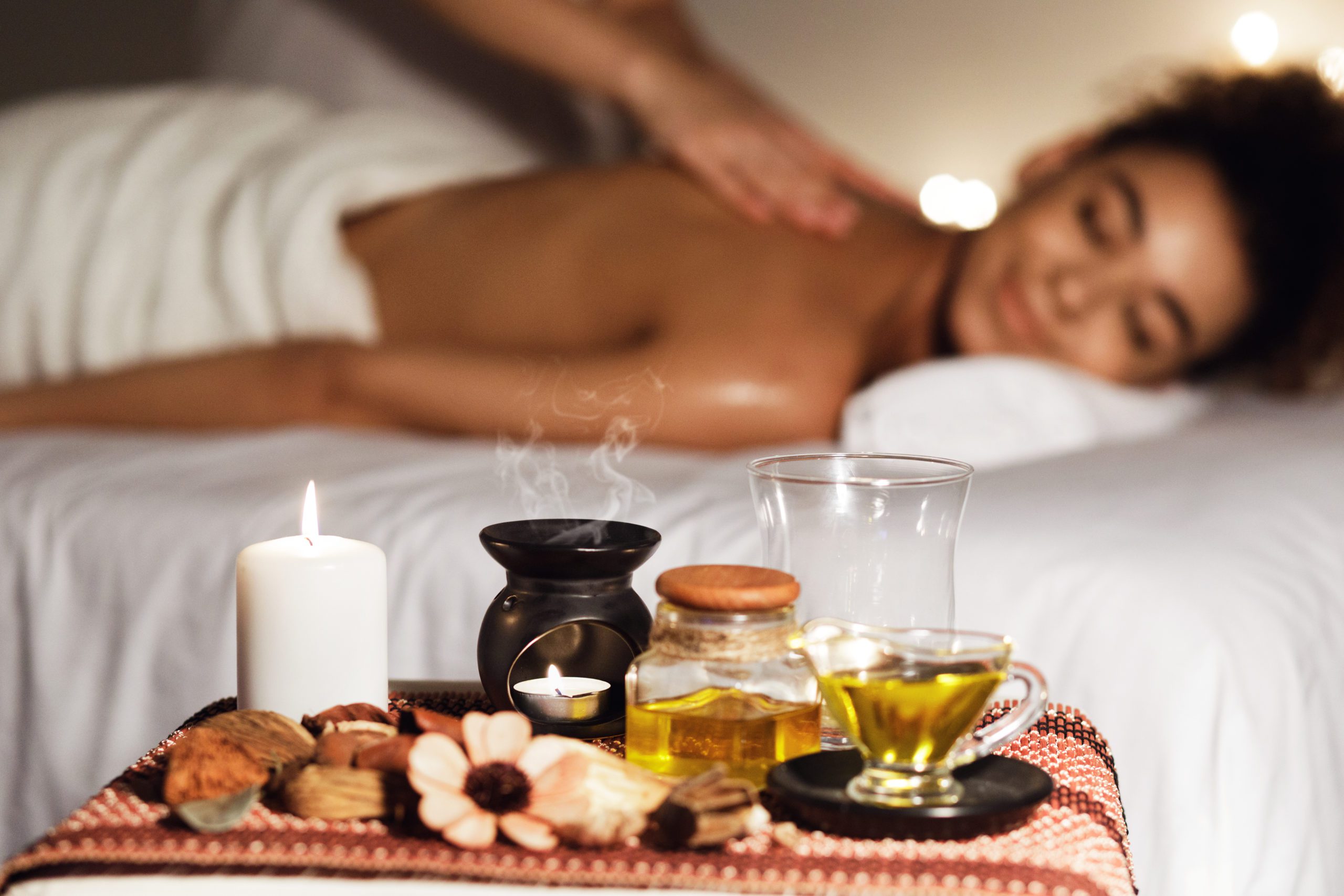 African woman enjoying aromatherapy massage in luxury spa African woman enjoying aromatherapy massage in luxury spa with candles on foreground